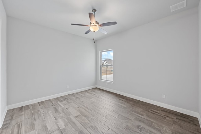 unfurnished room with a ceiling fan, baseboards, visible vents, and wood finished floors