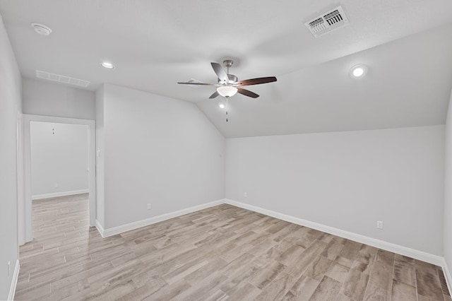 additional living space with visible vents, baseboards, ceiling fan, vaulted ceiling, and light wood-style floors