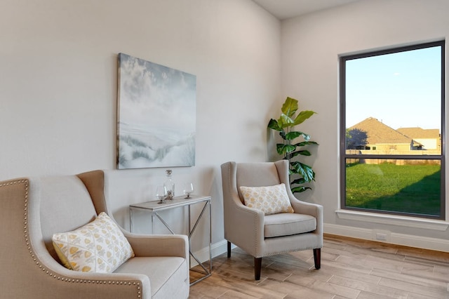 living area featuring a healthy amount of sunlight, baseboards, and wood finished floors