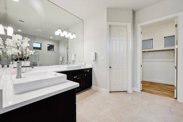 bathroom featuring visible vents, baseboards, a walk in closet, vanity, and a shower stall