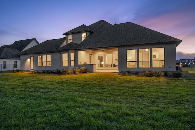 227 Dally Ct, Dripping Springs, TX 78620 - back of house at dusk featuring a lawn, stucco siding, and roof with shingles