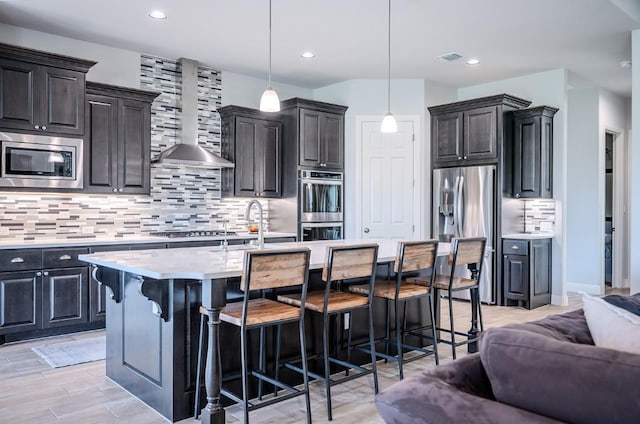 227 Dally Ct, Dripping Springs, TX 78620 - kitchen with stainless steel appliances, open floor plan, light countertops, wall chimney exhaust hood, and tasteful backsplash
