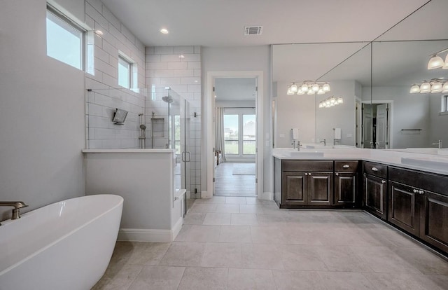227 Dally Ct, Dripping Springs, TX 78620 - bathroom with double vanity, a stall shower, a freestanding tub, tile patterned flooring, and baseboards