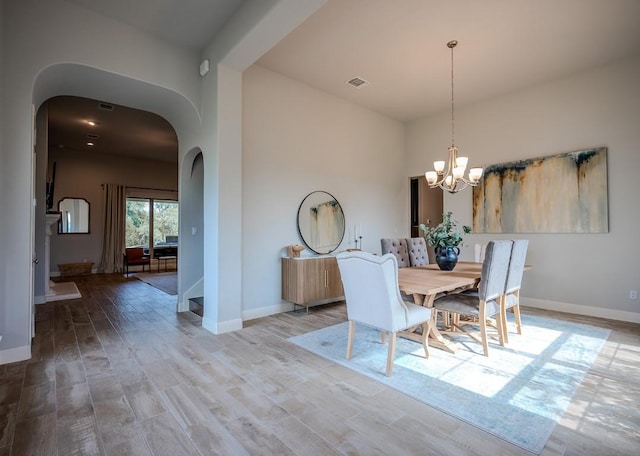 227 Dally Ct, Dripping Springs, TX 78620 - dining space featuring arched walkways, a chandelier, baseboards, and wood finished floors