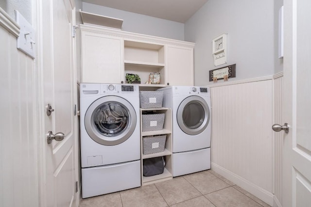 washroom featuring washing machine and dryer, wainscoting, cabinet space, and light tile patterned floors