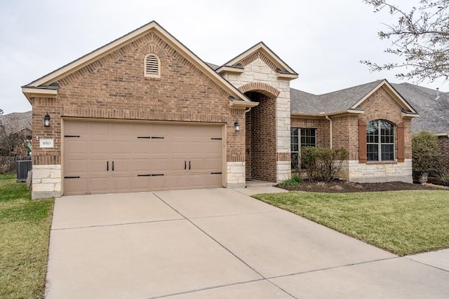 view of front facade featuring a garage, brick siding, stone siding, driveway, and a front yard