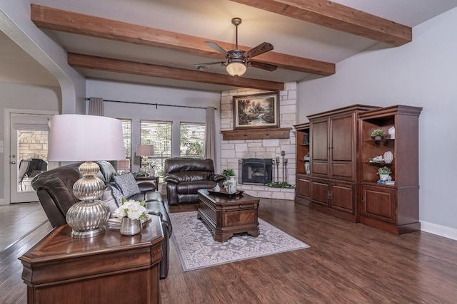 living area featuring a fireplace, wood finished floors, a ceiling fan, baseboards, and beam ceiling