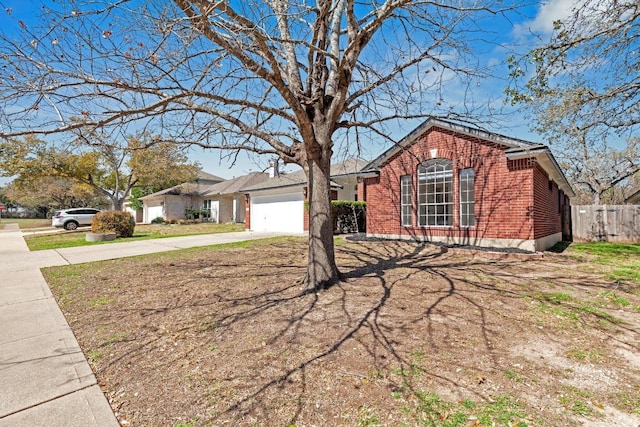 single story home with an attached garage, fence, concrete driveway, and brick siding