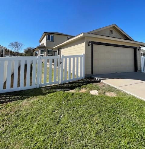 view of front of property with concrete driveway, a front lawn, an attached garage, and fence