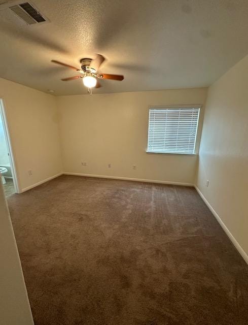 empty room with baseboards, visible vents, dark colored carpet, and a ceiling fan