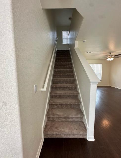 stairs featuring ceiling fan, baseboards, and wood finished floors