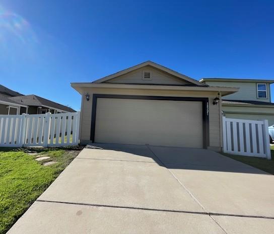 view of front facade with a garage, concrete driveway, and fence