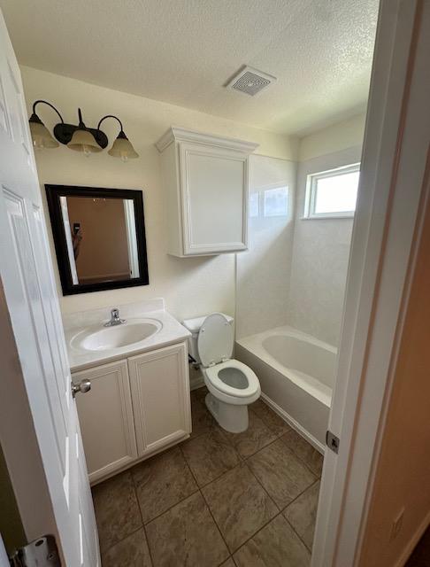 full bath with a textured ceiling, toilet, vanity, visible vents, and tile patterned floors