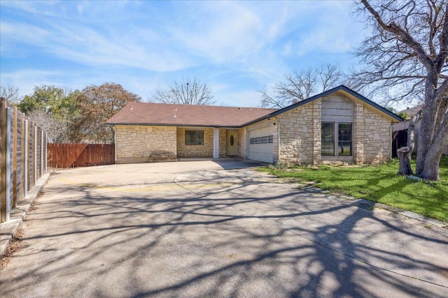 view of front of property with a garage, concrete driveway, stone siding, fence, and a front yard