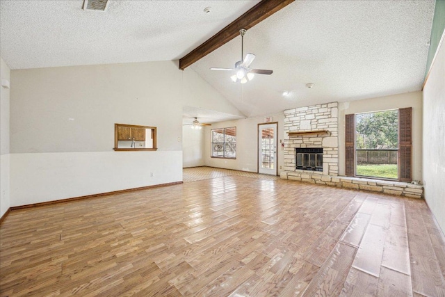 unfurnished living room featuring a wealth of natural light, a fireplace, beamed ceiling, and wood finished floors