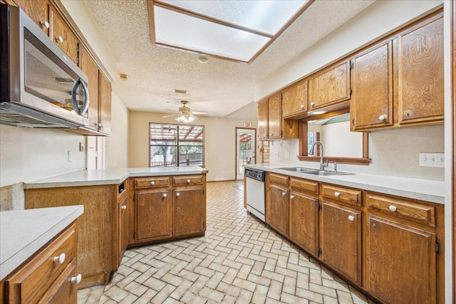 kitchen with light countertops, stainless steel microwave, white dishwasher, a sink, and a peninsula