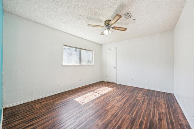 empty room featuring ceiling fan, a textured ceiling, visible vents, baseboards, and dark wood-style floors