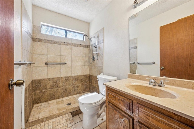 bathroom with toilet, vanity, a textured ceiling, and tiled shower