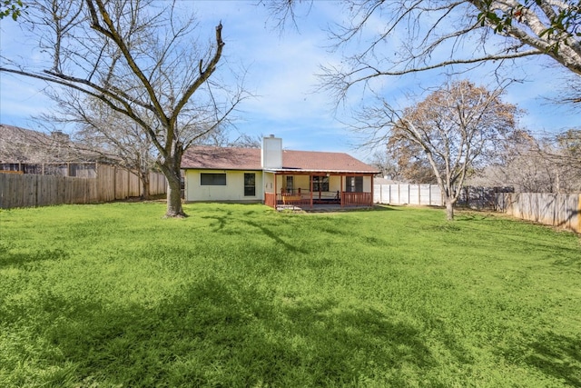 rear view of house featuring a fenced backyard, a chimney, and a lawn