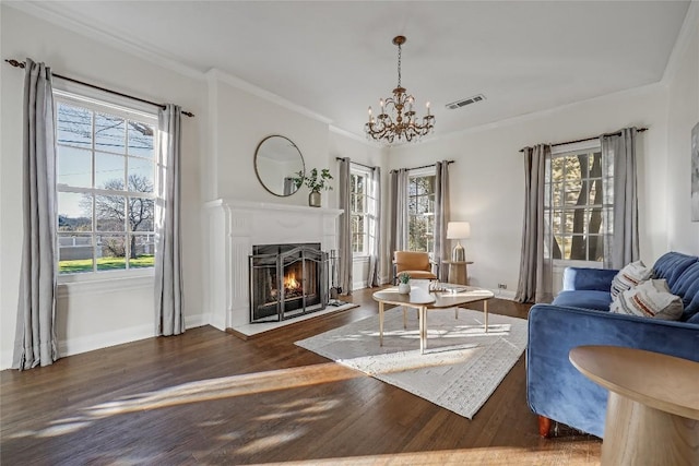 living area featuring plenty of natural light, a lit fireplace, visible vents, and wood finished floors