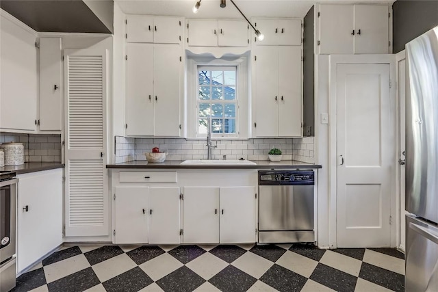 kitchen with stainless steel appliances, a sink, decorative backsplash, and tile patterned floors