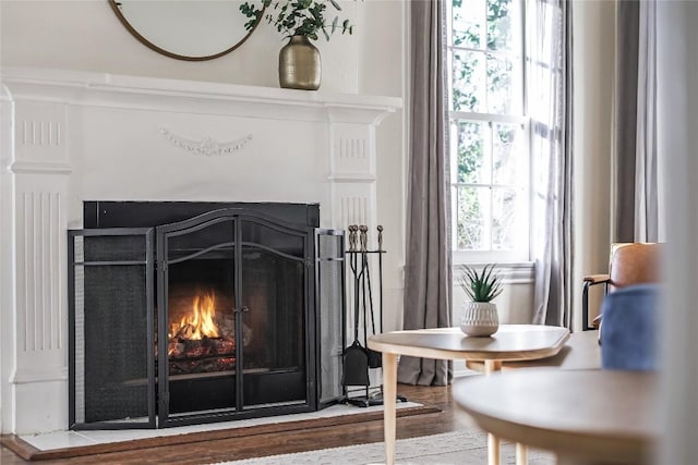 details with a warm lit fireplace and wood finished floors