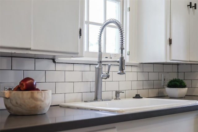 interior details with tasteful backsplash, white cabinets, and a sink