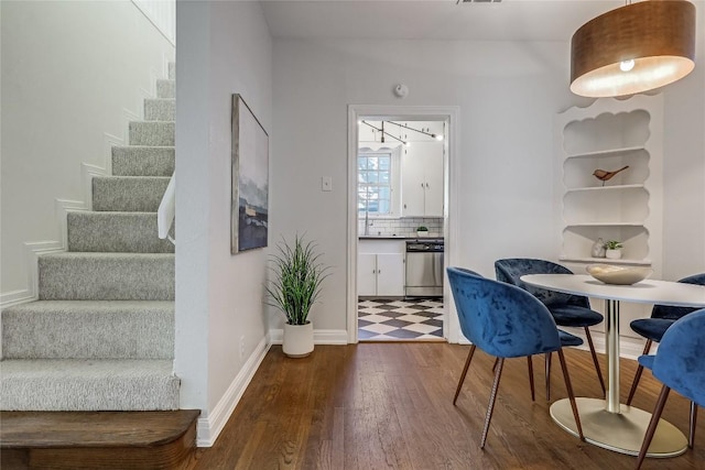 dining area featuring stairs, baseboards, and wood finished floors