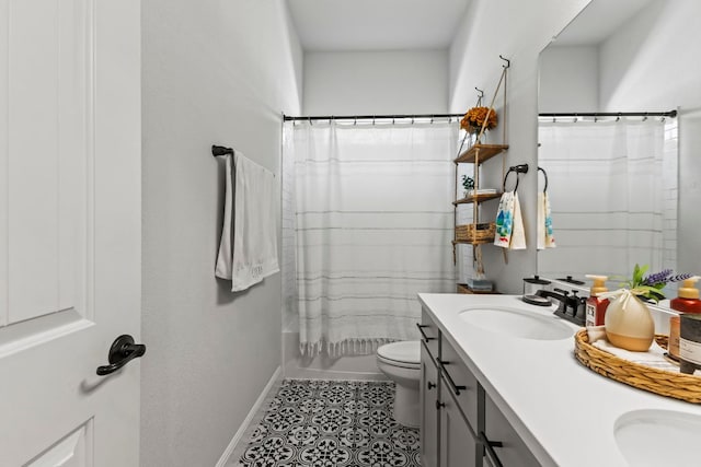 bathroom featuring double vanity, a sink, toilet, and baseboards