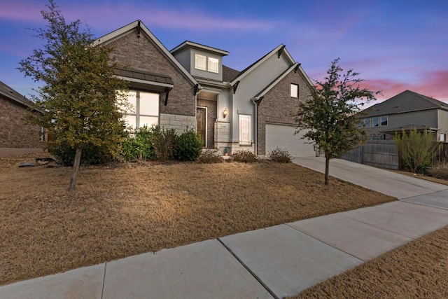 view of front of home featuring a garage, brick siding, fence, concrete driveway, and stone siding