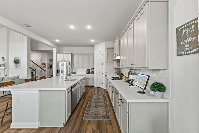 kitchen featuring a sink, visible vents, light countertops, appliances with stainless steel finishes, and dark wood-style floors