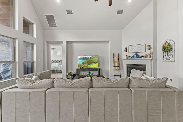 living area featuring lofted ceiling, a glass covered fireplace, and visible vents