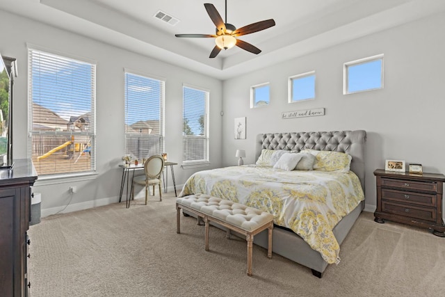 bedroom with carpet floors, a raised ceiling, visible vents, ceiling fan, and baseboards