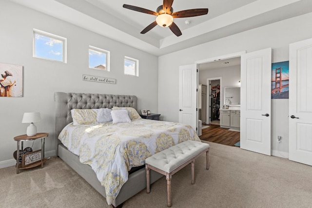 bedroom featuring carpet floors, multiple windows, a raised ceiling, and baseboards