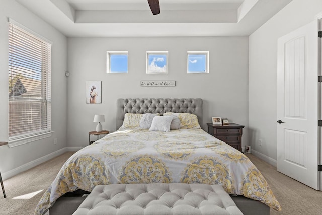 bedroom with a tray ceiling, carpet, and baseboards