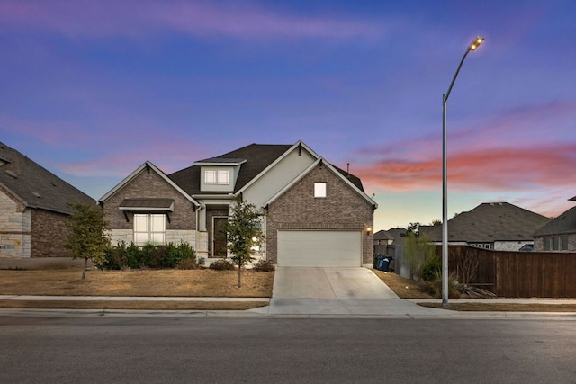 view of front of house featuring a garage, driveway, brick siding, and fence