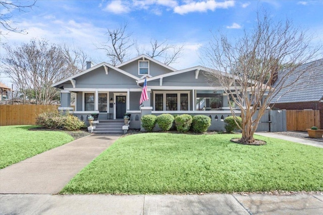 craftsman-style home featuring fence and a front lawn