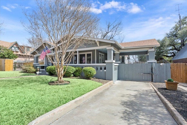 craftsman inspired home featuring an attached carport, a fenced front yard, concrete driveway, a gate, and a front lawn