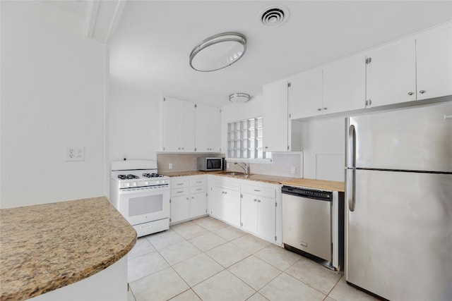 kitchen featuring stainless steel appliances, light countertops, visible vents, decorative backsplash, and white cabinetry