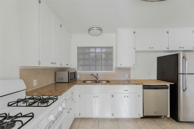 kitchen with light tile patterned floors, stainless steel appliances, a sink, and white cabinets