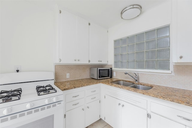 kitchen with white range with gas stovetop, stainless steel microwave, a sink, and decorative backsplash