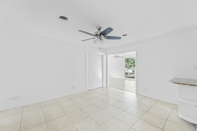 empty room featuring light tile patterned floors, visible vents, and a ceiling fan