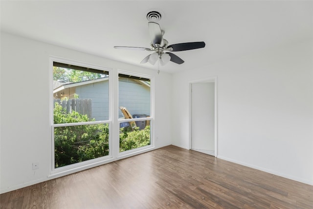 spare room featuring a ceiling fan, wood finished floors, visible vents, and baseboards