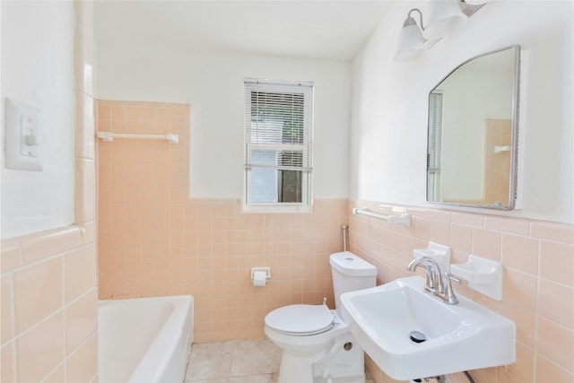 bathroom with wainscoting, toilet, a tub, tile patterned floors, and a sink