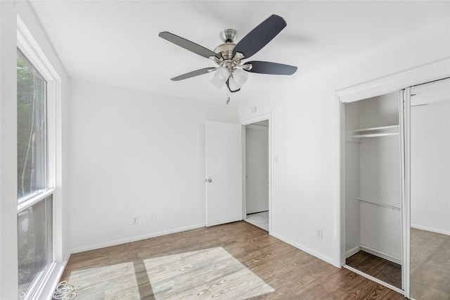 unfurnished bedroom with a ceiling fan, a closet, baseboards, and wood finished floors