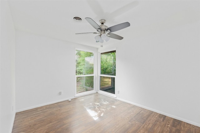 spare room featuring baseboards, visible vents, ceiling fan, and wood finished floors