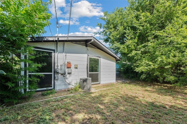 rear view of property with cooling unit and a lawn