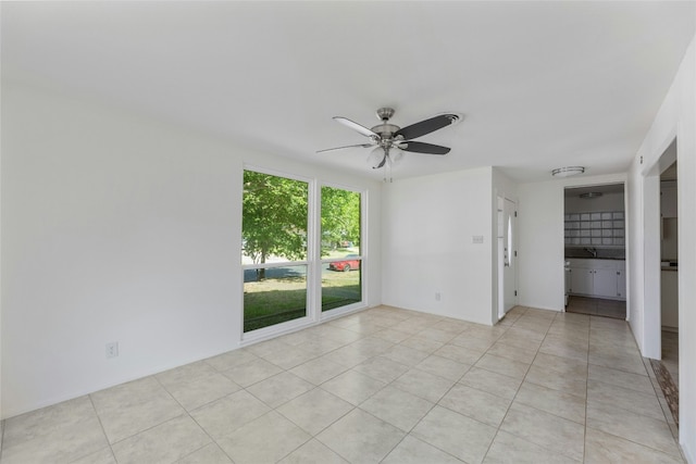 empty room with light tile patterned flooring, ceiling fan, and a sink