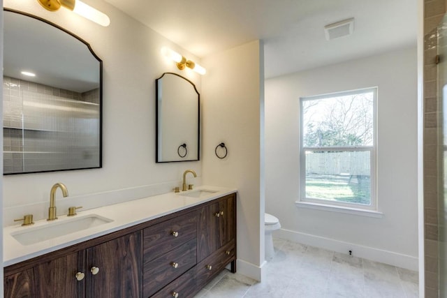 bathroom featuring toilet, double vanity, a sink, and visible vents