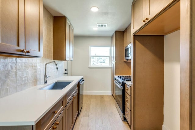 6401 Cooper Ln, Austin, TX 78745 - kitchen with appliances with stainless steel finishes, a sink, light wood finished floors, baseboards, and backsplash
